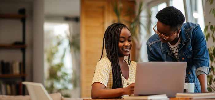 Student and parent using laptop and smiling.