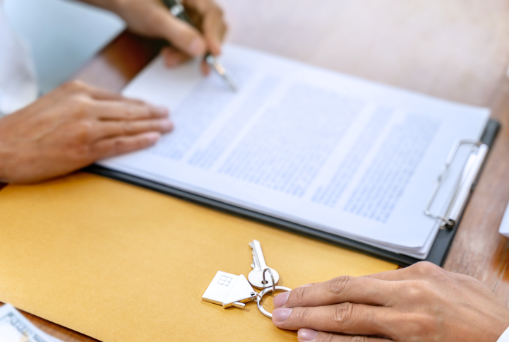 Close-up of someone reviewing a printed lease agreement and receiving a set of keys.