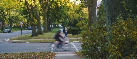 neighborhood street with student on foot and another on a bike