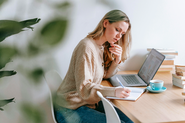 jeune fille à son bureau prend des note et profite d'un bon éclairage naturel