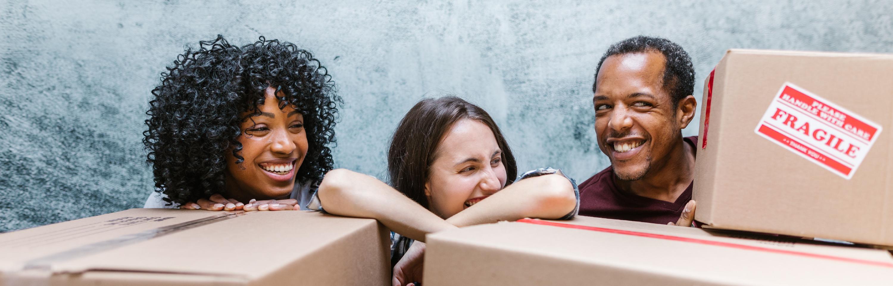 Three people smiling with moving boxes