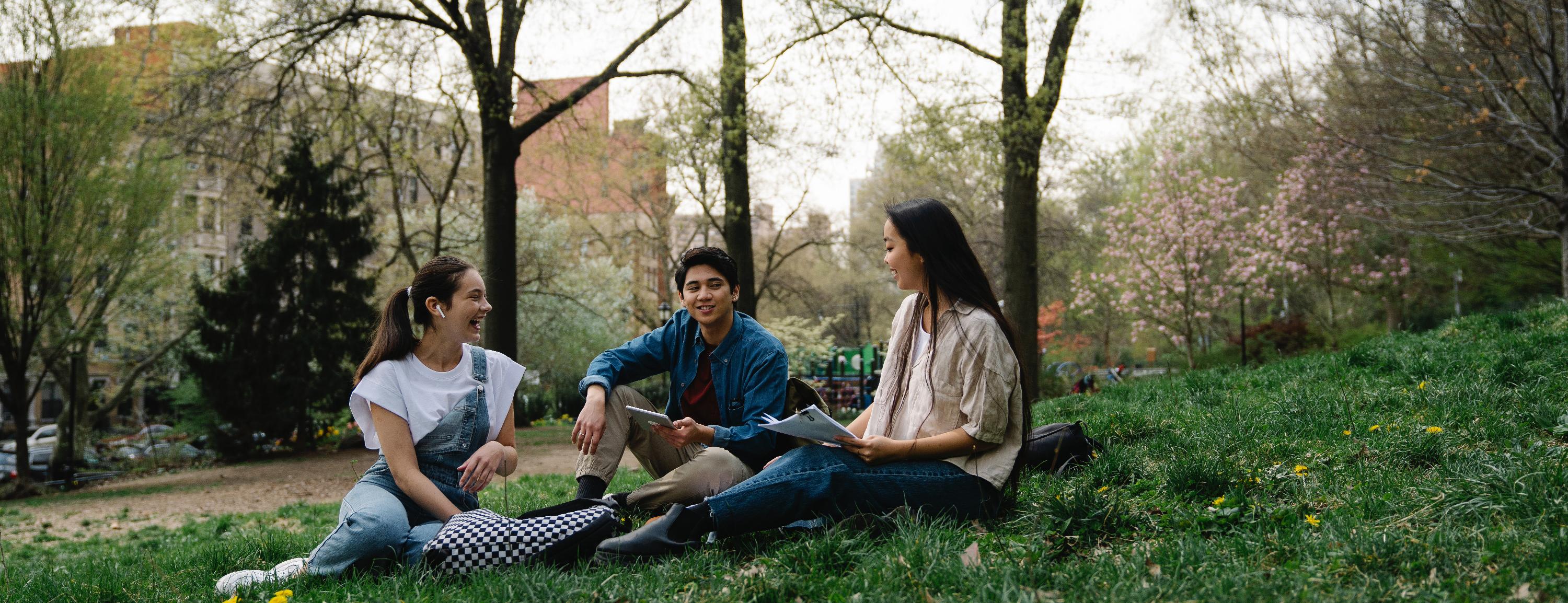 Three students laughing in grass