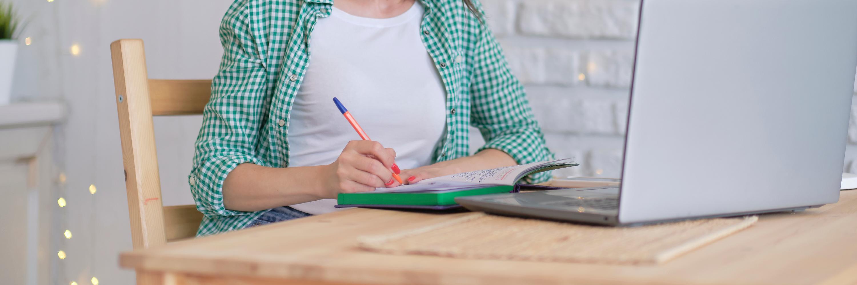 a person in front of a computer taking notes