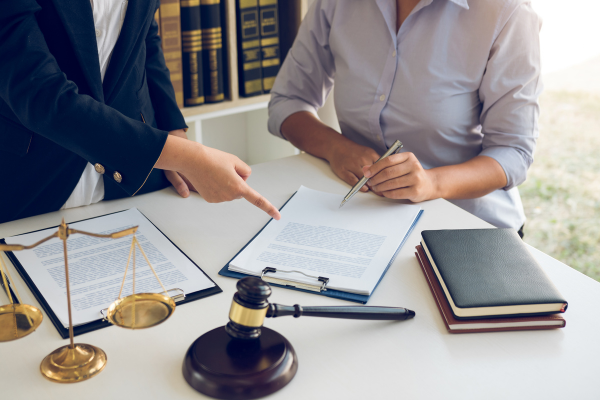 Two people sit at a table and review legal contracts