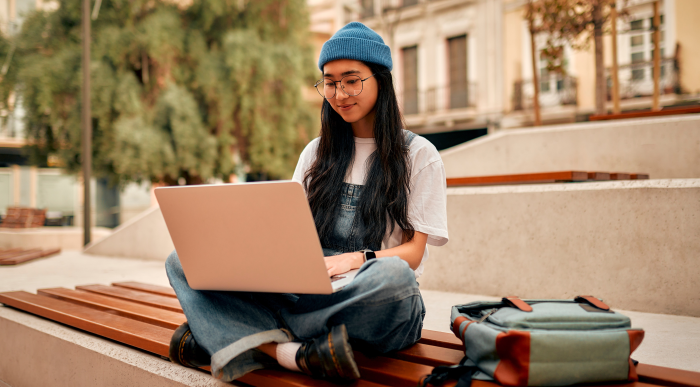 College student studying outdoors with a laptop.