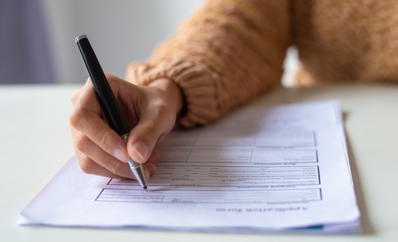 Close-up of someone completing an application form by hand.