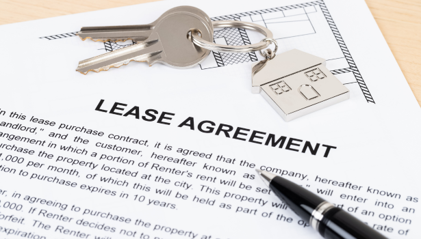 Close up of a set of keys sitting on top of a printed lease agreement.