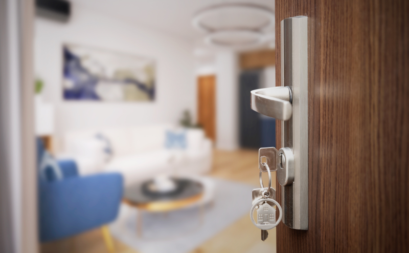 Close-up of front door partially open with keys dangling from the lock.