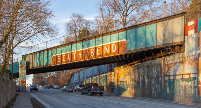 Covered bridge over a busy road, with “South Bend” painted on the wall