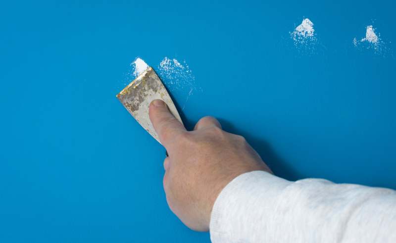 Close-up of someone covering nail holes with plaster.