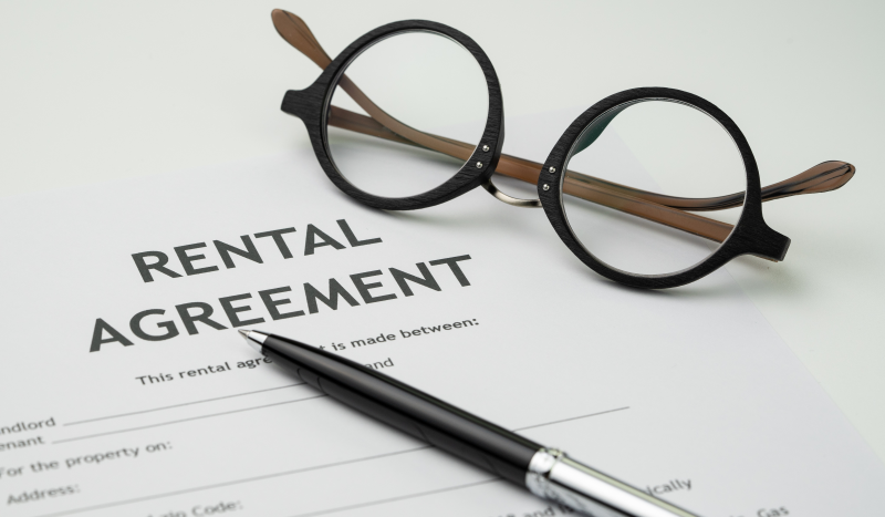 Close‑up of a rental agreement document with a pen and a pair of glasses on top