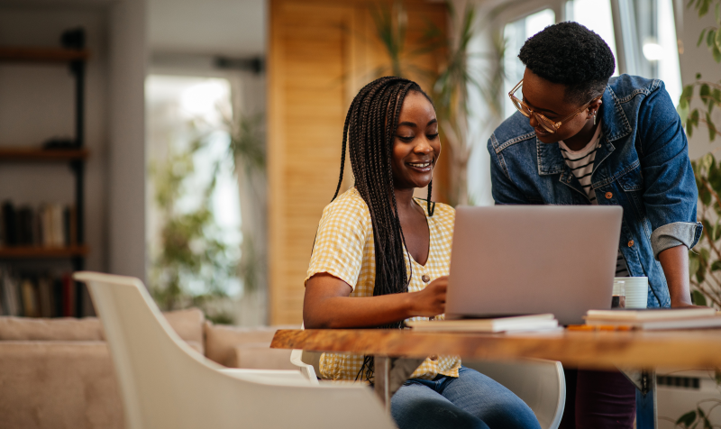Parent and child smile while looking at laptop together.