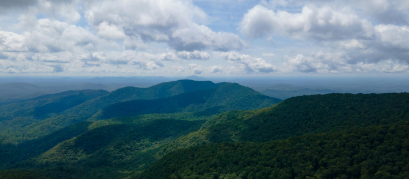Blue Ridge Mountains covered in green trees under a cloudy sky.