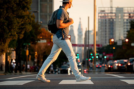 student walking across the street with Philly tall buildings in the background