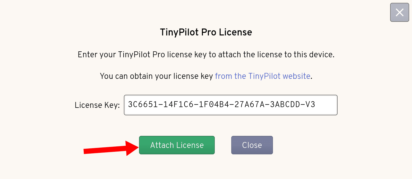 The TinyPilot License Dialog shows that the License Key input has been populated with a license key. A red arrow points to the green 'Attach License' button.
